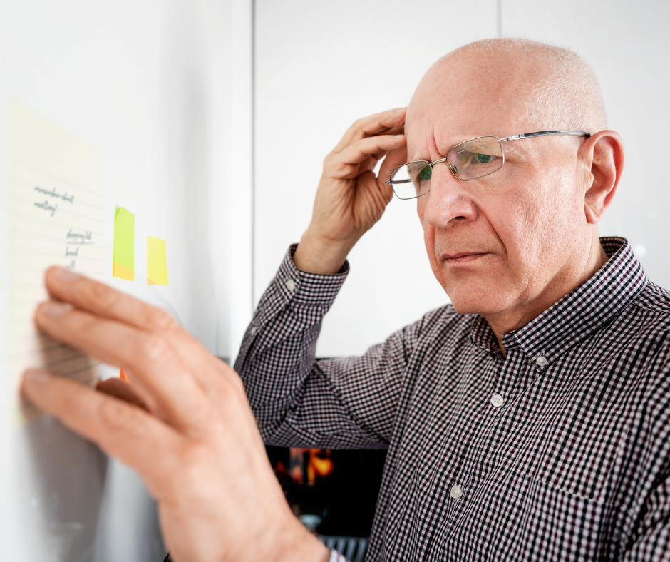 Older man looking at writing and Post It notes while scratching his head with a confused look