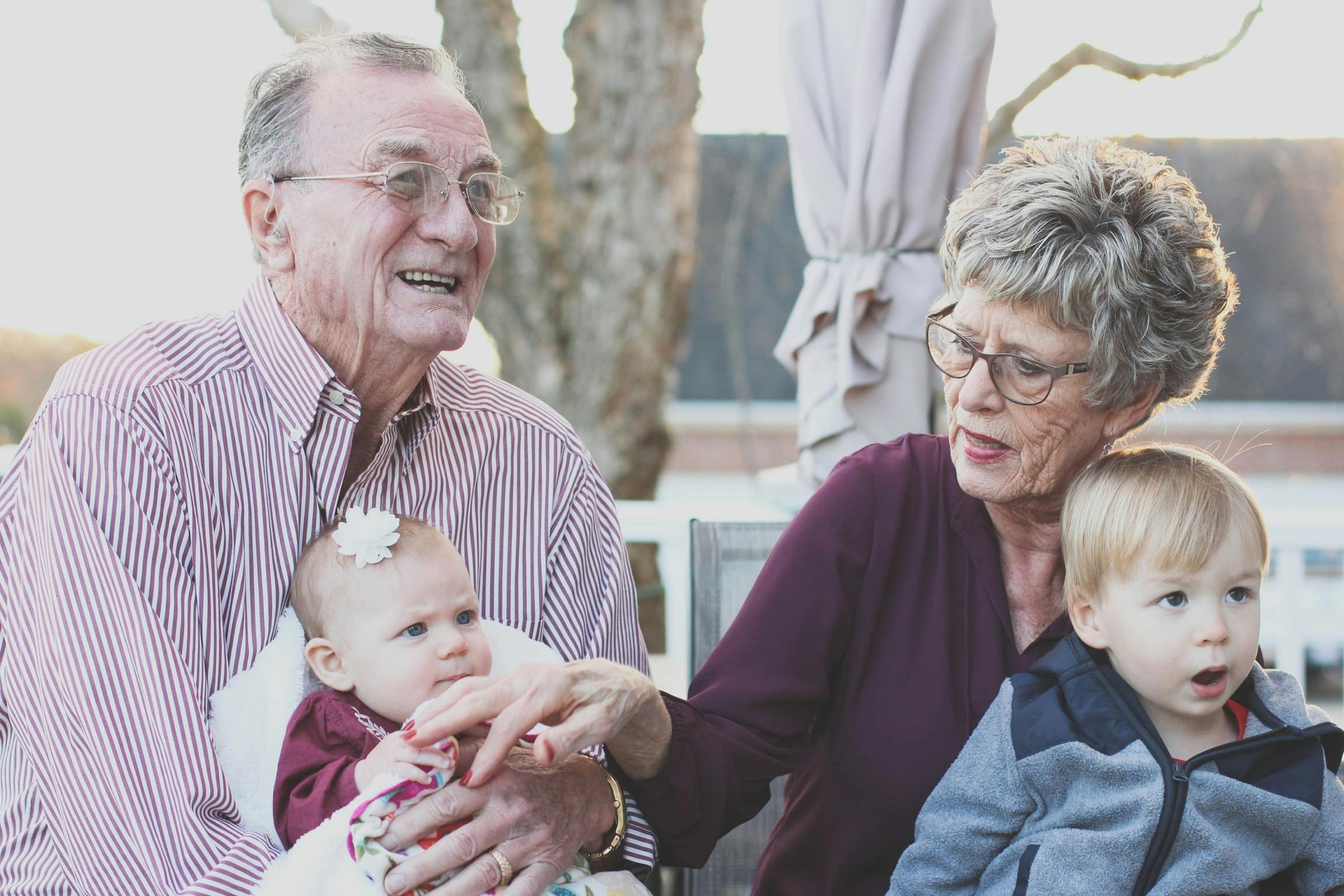 Elderly couple holding babies.